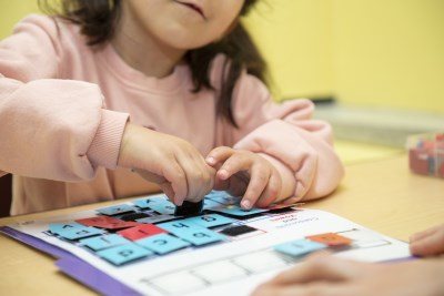 Student moving small lettered tiles around on a desk