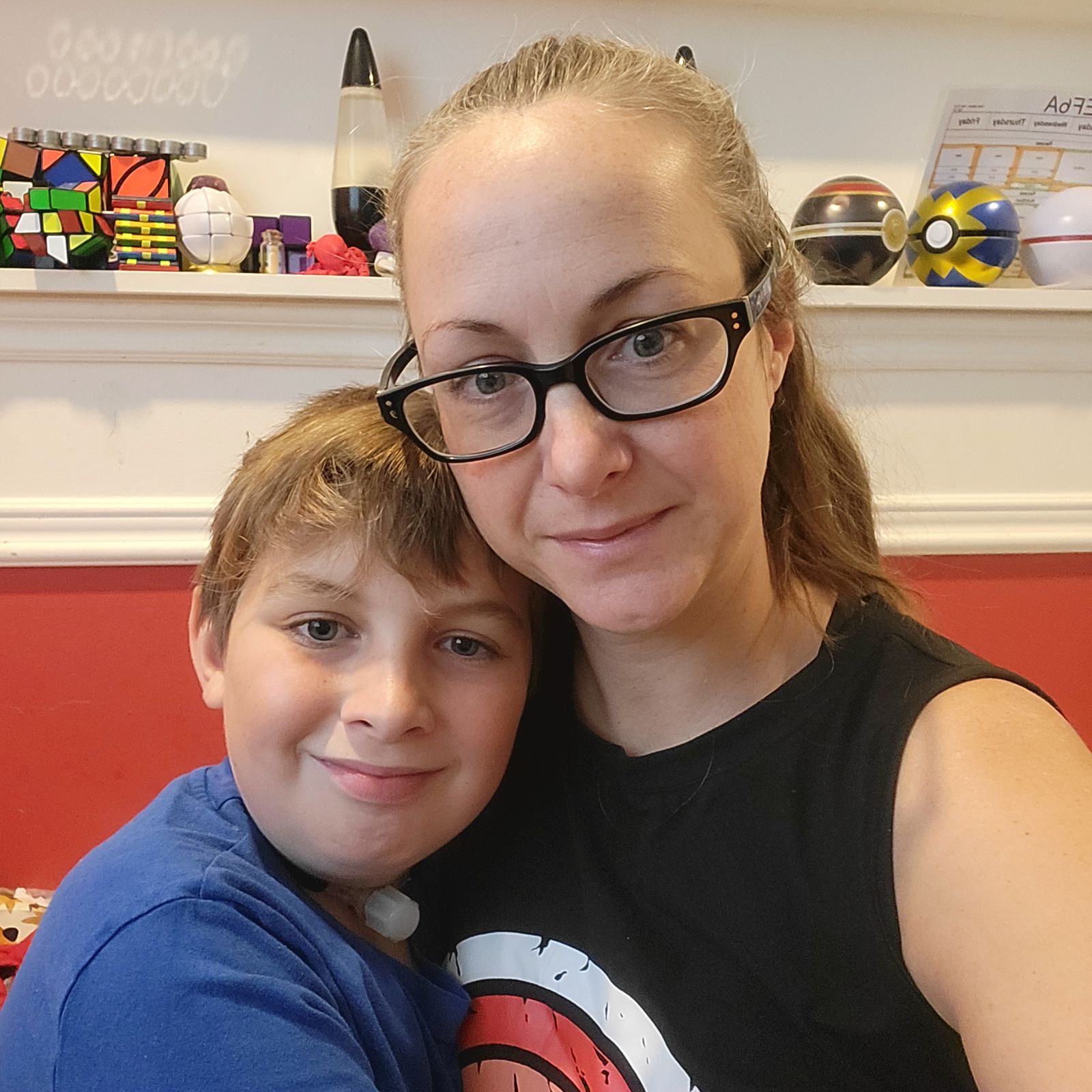 mother and son sit in boy's bedroom with toys in background