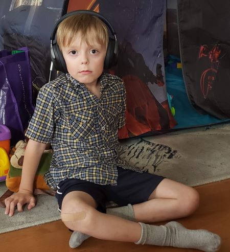 boy sits with headphones on looking at camera