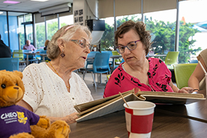 mother and daughter look at photo album sitting in cafeteria