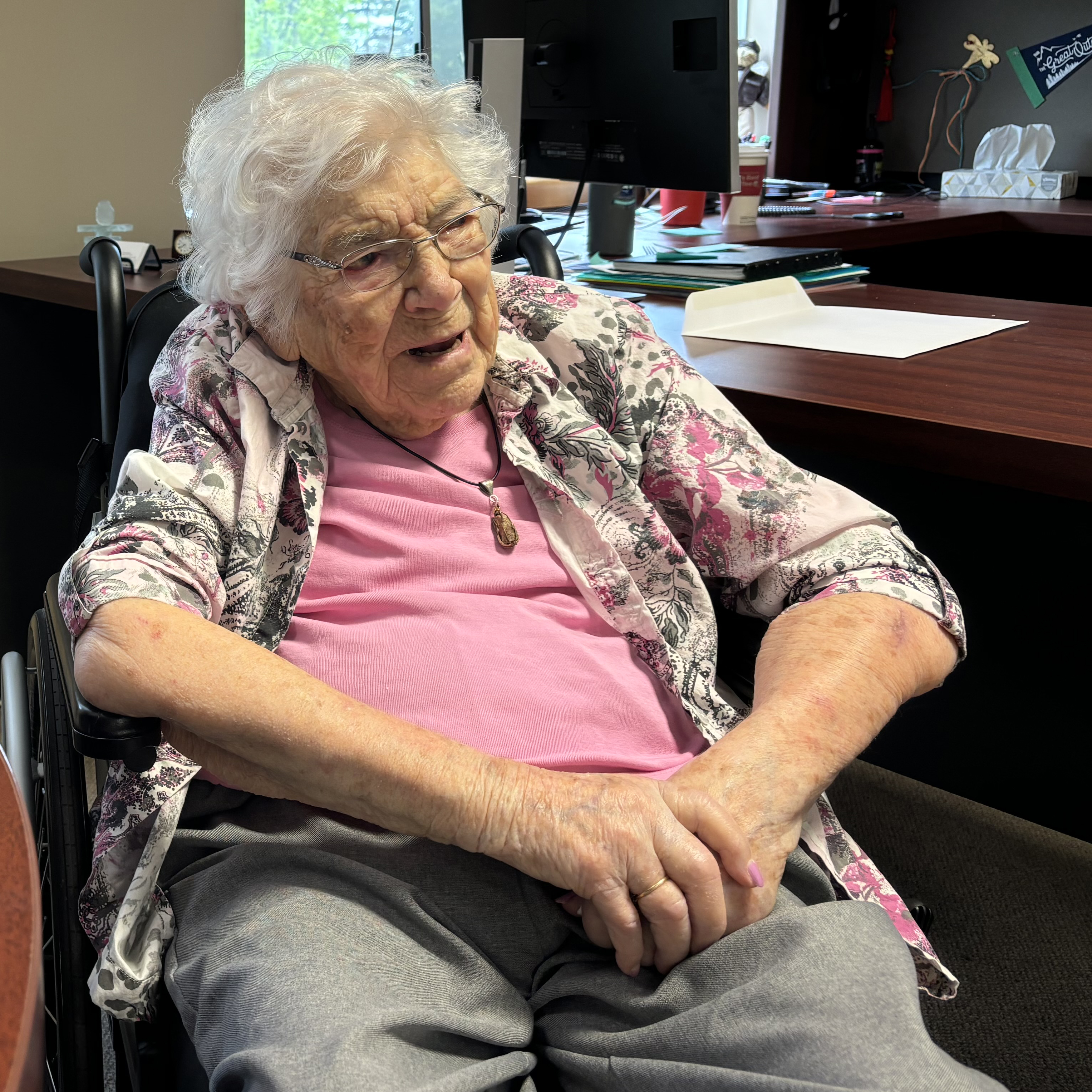 108 year old woman sits in a wheelchair talking to cheo staff member in an office