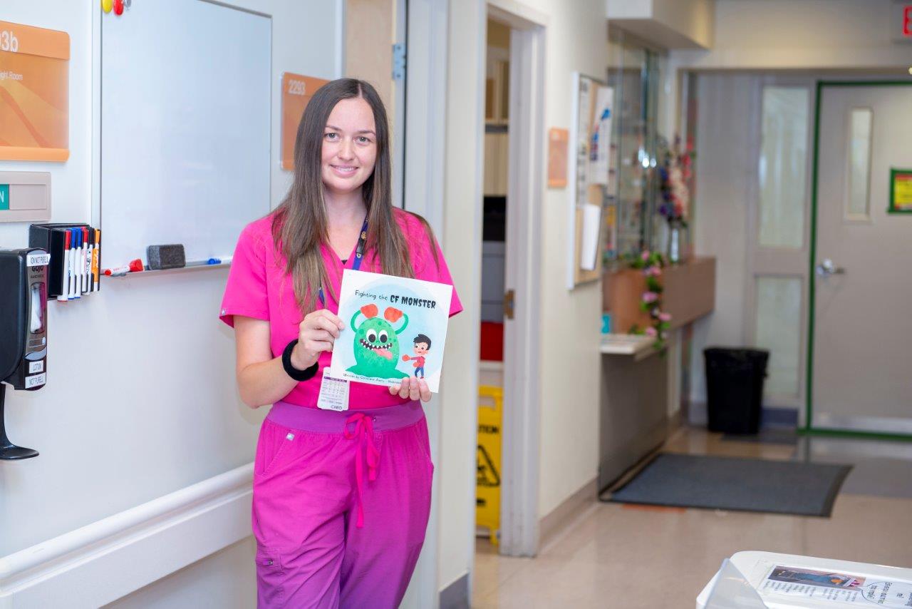 Michelle Vander Meer. She wears pink scrubs and holds a children's book.