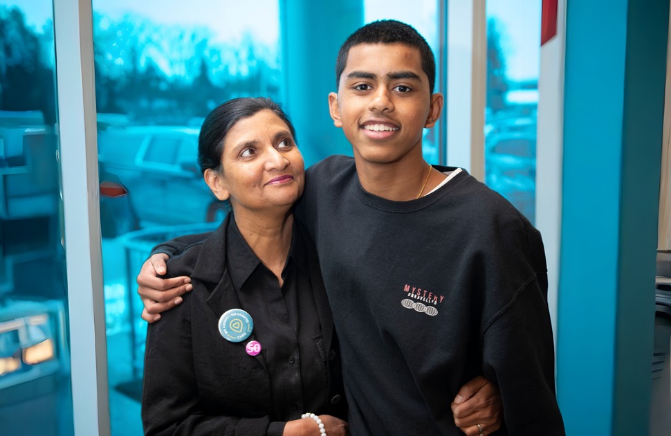 A woman standing next to her son in front of a window